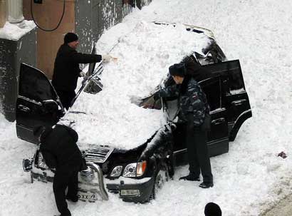 Сугроб снега упал с крыши на машину